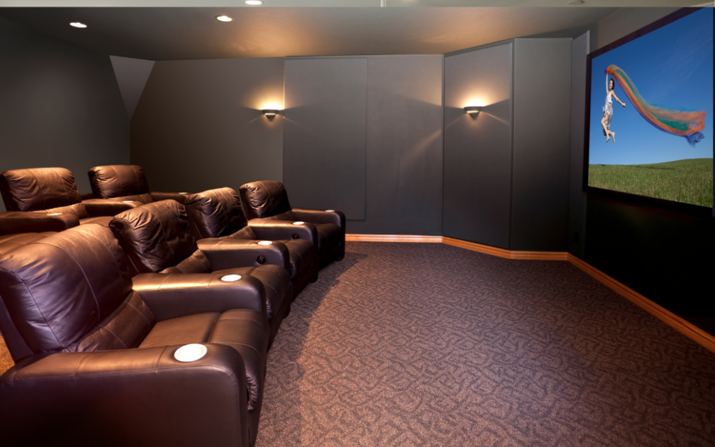Dedicated home cinema featuring a ceiling-mounted projector, large projection screen, and surround sound speakers for a cinematic experience.